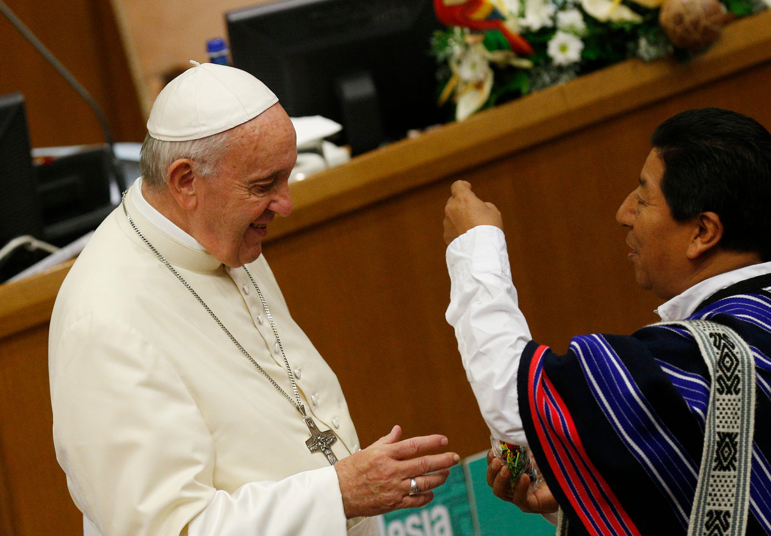 An unidentified man presents a neckerchief to Pope Francis at the start of a session of the Synod of Bishops for the Amazon at the Vatican Oct. 15, 2019.